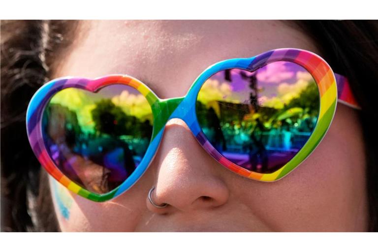 Eine Person, die eine Sonnenbrille mit Regenbogenherz trägt, beobachtet die World Pride Parade in Washington.
