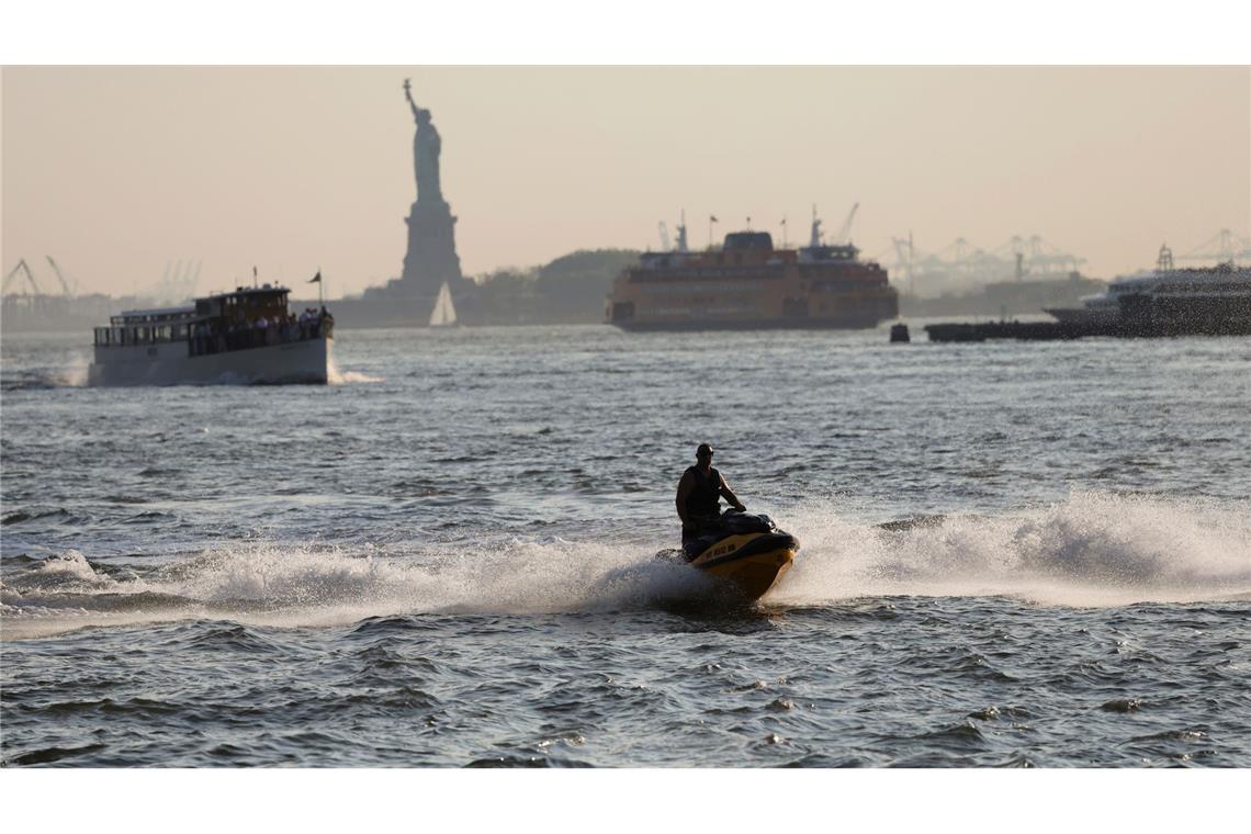 Bilder des Tages Eine Person fährt in New York auf einem Jetski im East River mit der Freiheitsstatue im Hintergrund. Wegen des Rauchs der Waldbrände in Kanada wurde für die Region New York eine Luftqualitätswarnung herausgegeben.