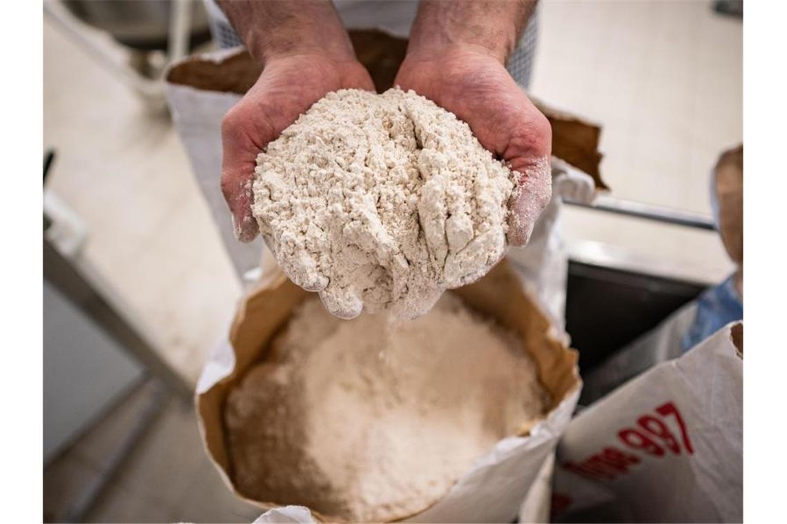 Unbekannte bewerfen Zug mit Mehl Eine Person hält Bio-Dinkelmehl in den Händen. Darunter befindet sich eine Mehl-Verpackung. Foto: Frank Rumpenhorst/dpa/Archivbild
