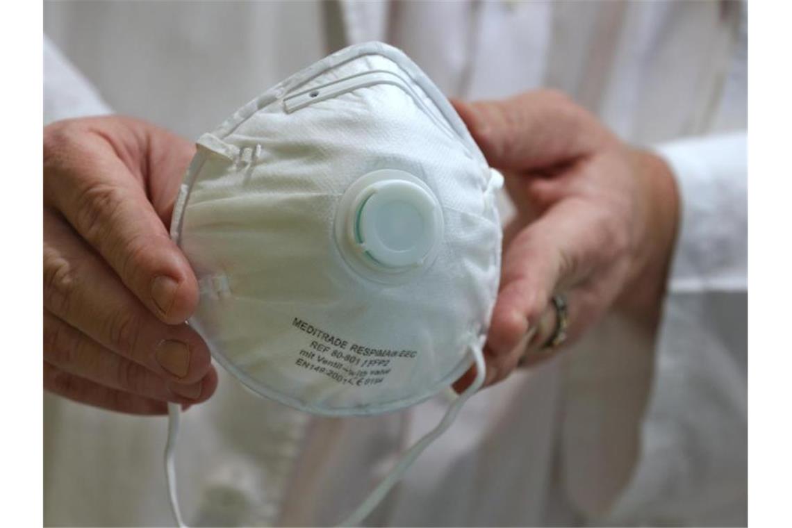 Eine Person hält eine Atemschutzmaske in den Händen. Foto: Karl-Josef Hildenbrand/dpa/Archivbild