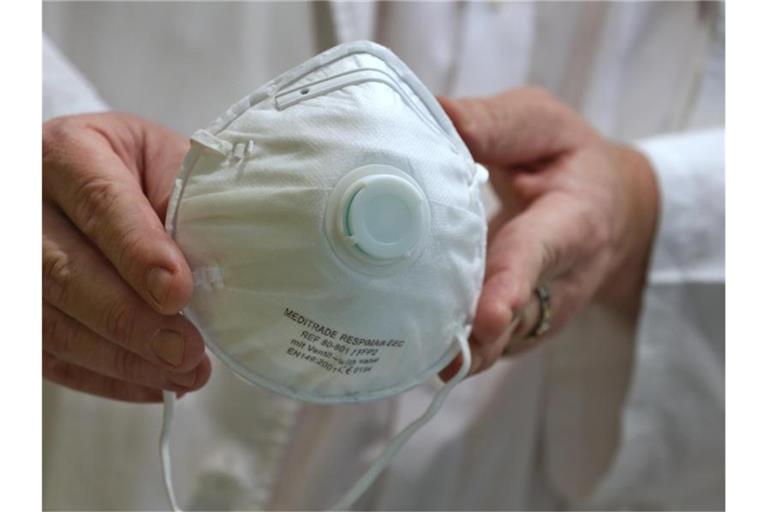 Eine Person hält eine Atemschutzmaske in den Händen. Foto: Karl-Josef Hildenbrand/dpa/Archivbild