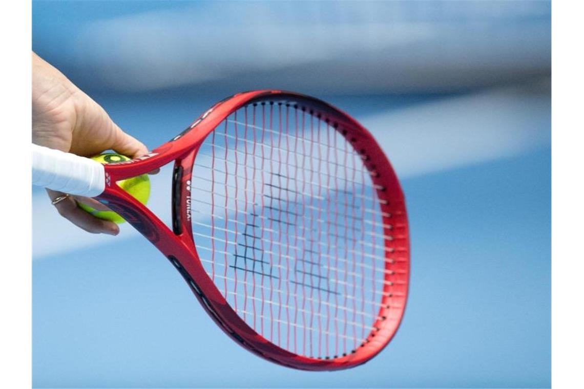 Eine Person hält einen Tennisschläger und einen Tennisball in der Hand. Foto: Julian Stratenschulte/dpa/Symbolbild