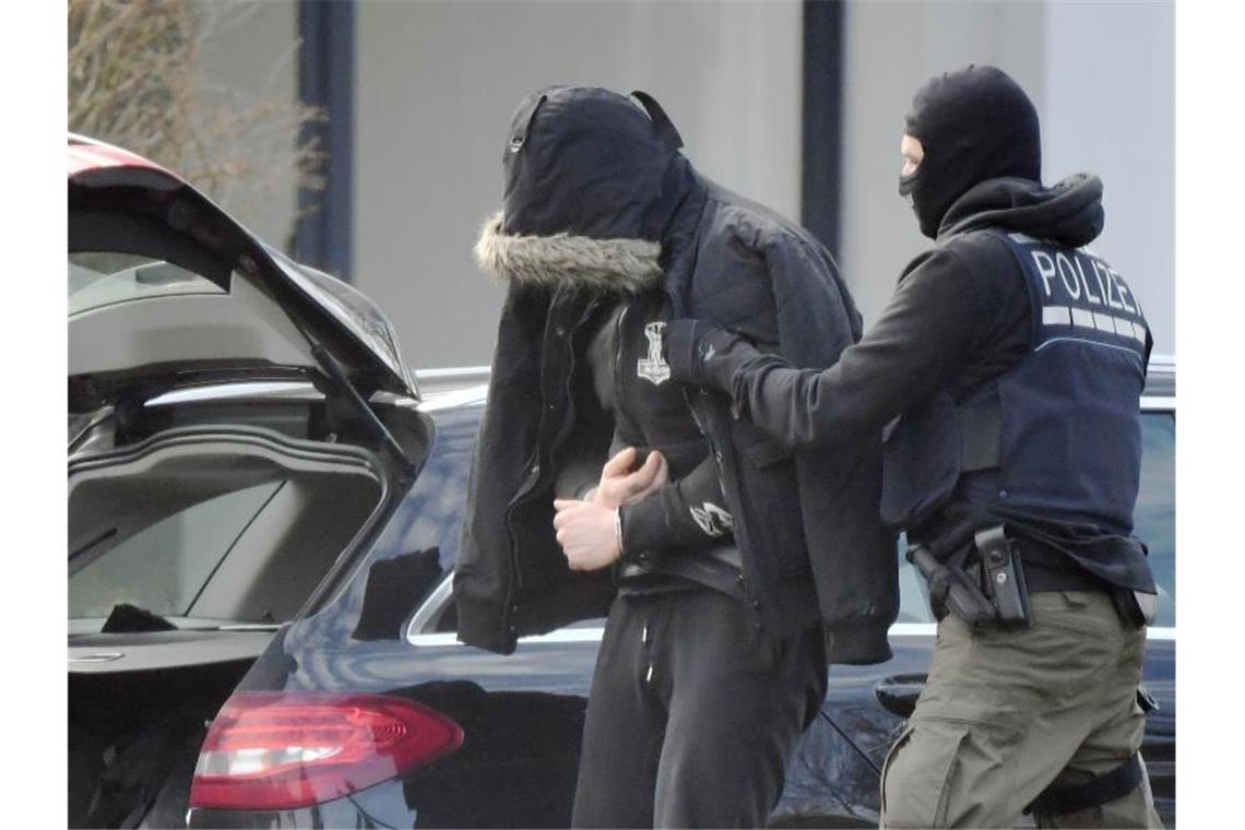 Eine Person wird von einem maskierten Polizisten in den Bundesgerichtshof in Karlsruhe gebracht. Foto: Uli Deck/dpa