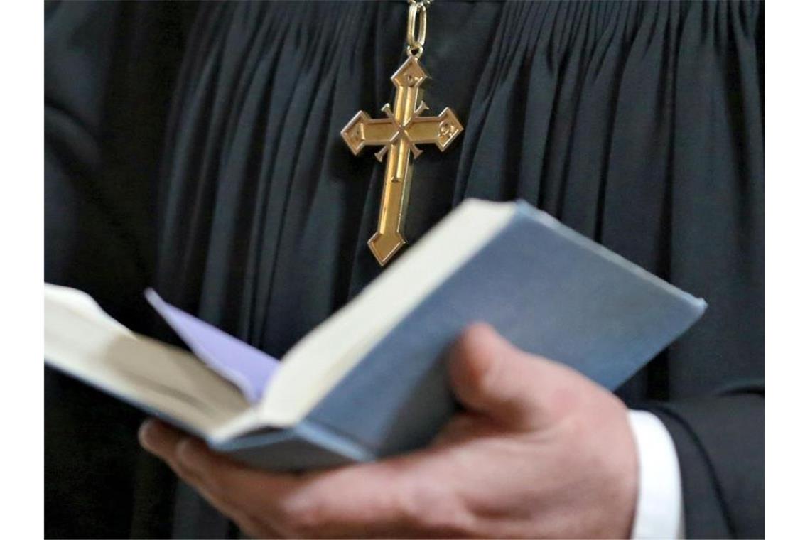 Landessynode entscheidet über Geld für Kirchengemeinden Eine Pfarr-Person hält eine Bibel in den Händen. Foto: Jan Woitas/dpa-Zentralbild/dpa/Archivbild