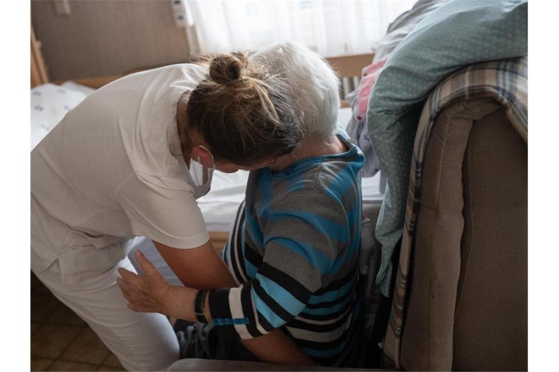 Im Südwesten Zuzahlung für Pflege im Heim besonders hoch Eine Pflegefachkraft hilft in der ambulanten Pflege einer Frau beim Umsetzen. Foto: Sebastian Gollnow/dpa/Symbolbild