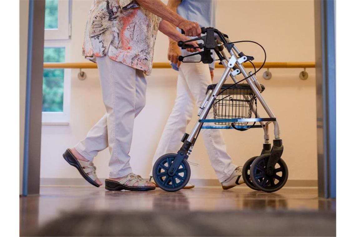 Spahn plant massenhaft Coronatests in Pflegeheimen Eine Pflegekraft geht in einem Pflegeheim mit einer älteren Dame über einen Korridor. Alten- und Pflegeheime sollen ab dem 15. Oktober flächendeckend Coronatests durchführen. Foto: Christoph Schmidt/dpa