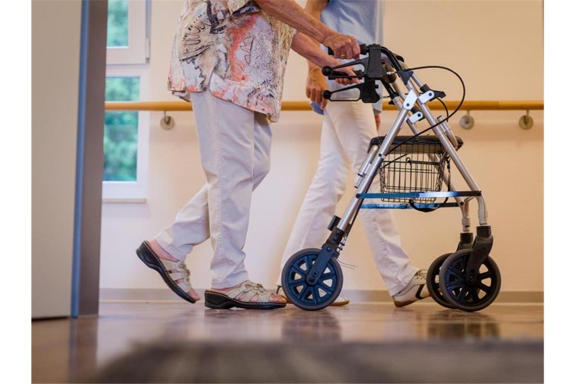 Pflegebevollmächtigter warnt vor „Isolation um jeden Preis“ Eine Pflegekraft geht in einem Pflegeheim mit einer älteren Dame über einen Korridor. Foto: Christoph Schmidt/dpa