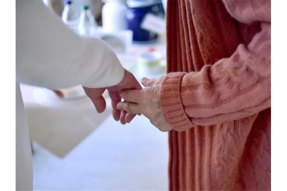 Eine Pflegekraft hält die Hand einer Bewohnerin einer Pflegeeinrichtung. Foto: Britta Pedersen/dpa-Zentralbild/dpa/Archivbild