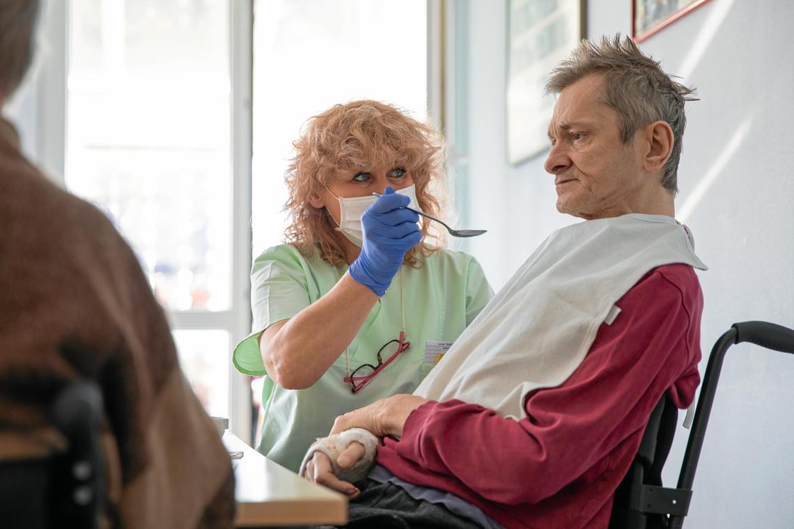 Eine Pflegerin füttert einen Bewohner im Pflegeheim der Erlacher Höhe. Maske und Handschuhe gehören mittlerweile zum Alltag. Foto: A. Becher