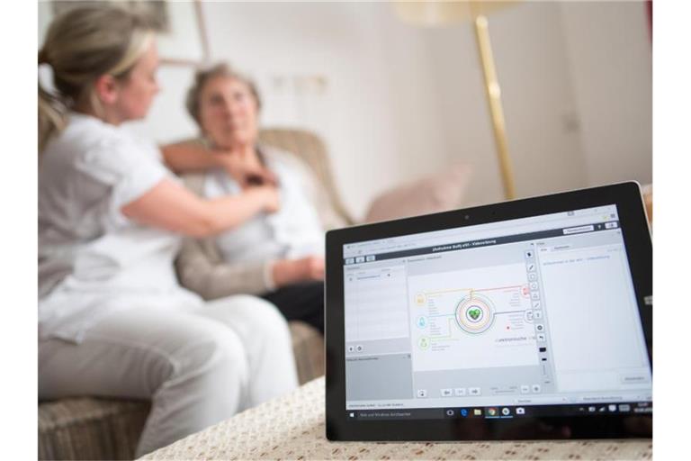 Eine Pflegerin legt einer Bewohnerin im Rahmen einer elektronischen Visite ein EKG-Gerät an, dass die Daten an einen Tablet-Computer und von dort aus zum Arzt überträgt. Foto: Marius Becker