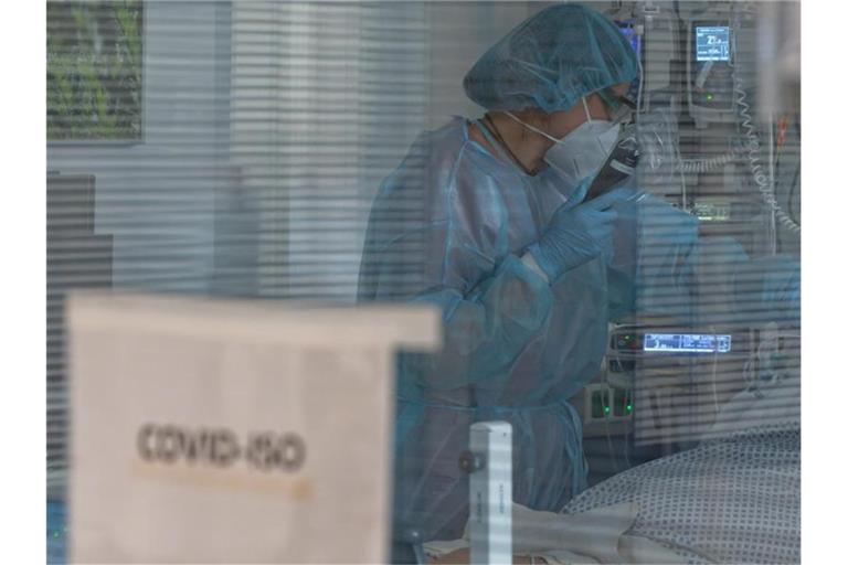 Eine Pflegerin versorgt in der Intensivstation eines Krankenhauses einen Coronapatienten. Foto: Henning Kaiser/dpa