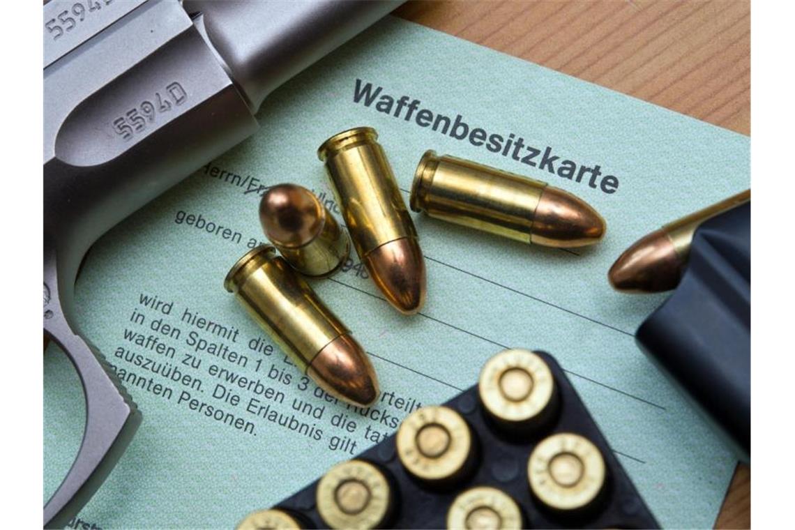 Eine Pistole und Patronen auf einer Waffenbesitzkarte. Foto: Patrick Pleul/dpa-Zentralbild/dpa/Illustration