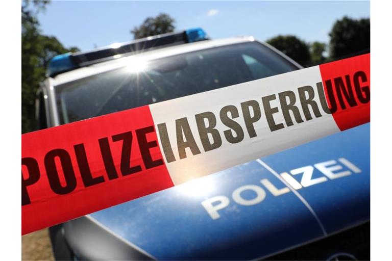 Eine Polizeiabsperrung hängt vor einem Polizeiauto. Foto: Bernd Wüstneck/ZB/dpa/Symbolbild