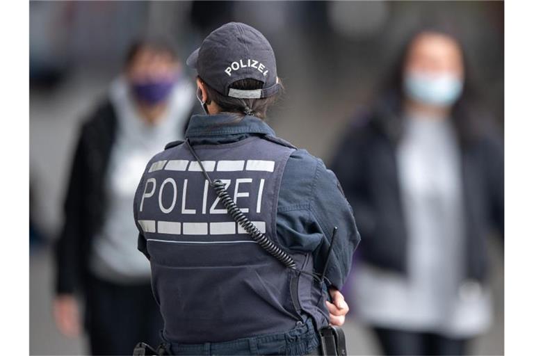 Eine Polizistin Blickt zu Passanten mit Masken. Foto: Sebastian Gollnow/dpa/Symbolbild