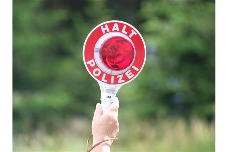 Eine Polizistin hält während einer Polizeikontrolle eine rote Winkerkelle in die Höhe. Foto: Sebastian Willnow/zb/dpa/Archivbild