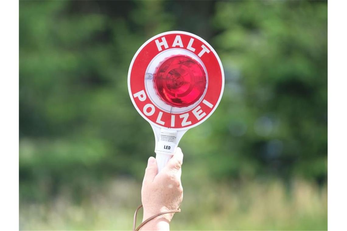 Eine Polizistin hält während einer Polizeikontrolle eine rote Winkerkelle in die Höhe. Foto: Sebastian Willnow/zb/dpa/Symbolbild