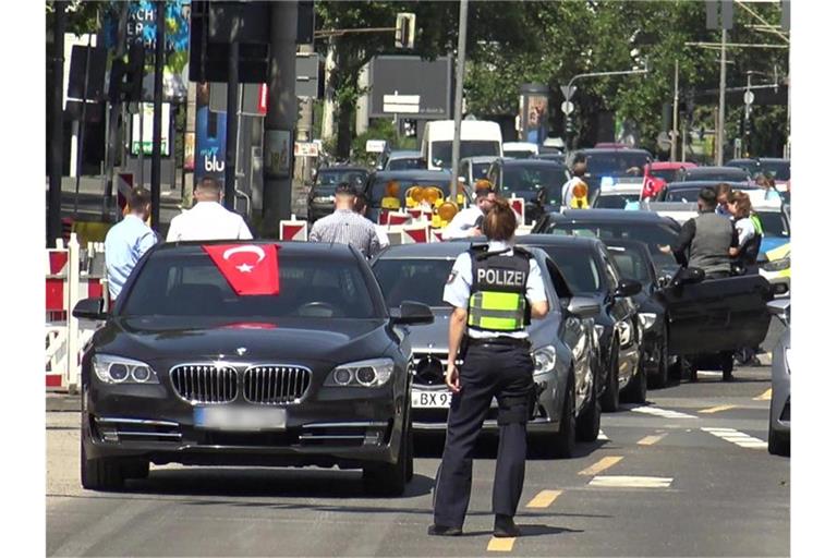 Eine Polizistin steht vor den Fahrzeugen eines türkischen Hochzeutskorsos. Foto: Thomas Kraus/dpa