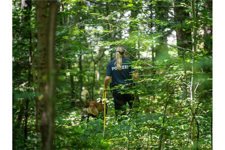 Eine Polizistin sucht mithilfe eines Suchhundes in einem Waldstück nach Hinweisen. Foto: Lino Mirgeler