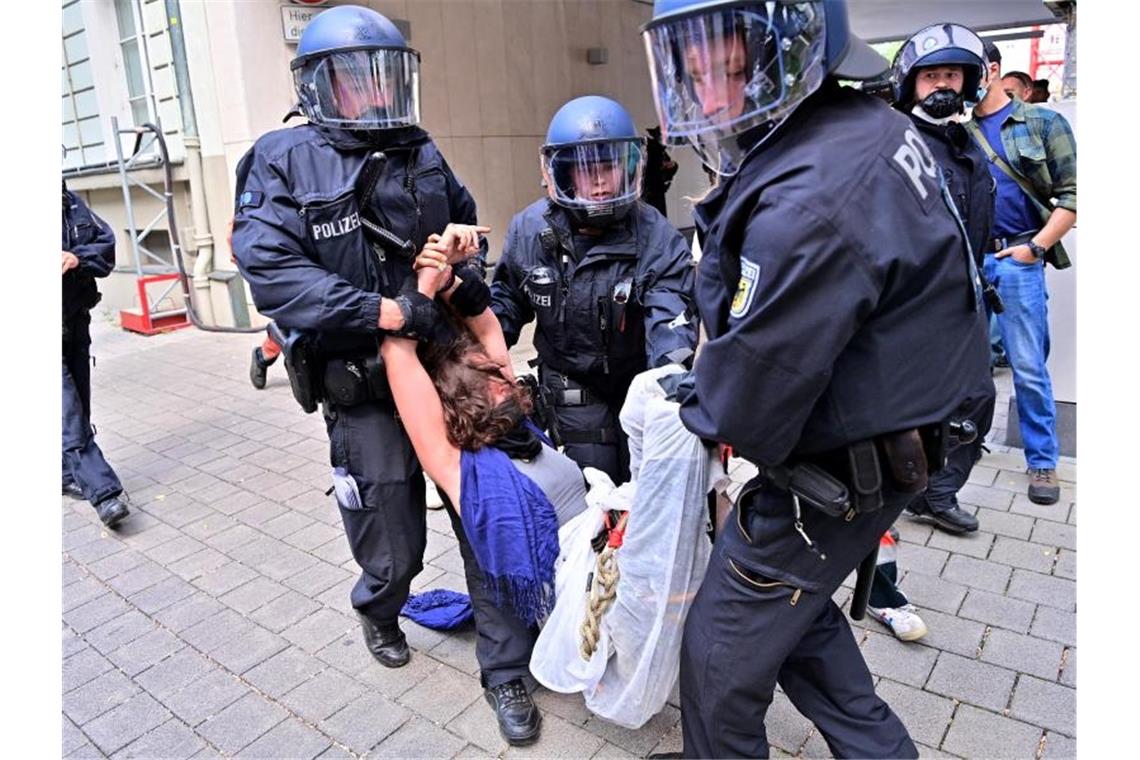 Eine Protestteilnehmerin wird von Polizisten weggetragen. Foto: Peter Kneffel/dpa