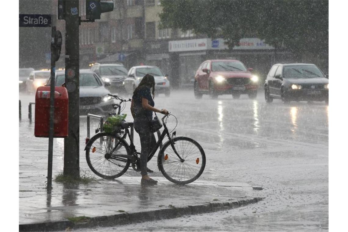 Eine Radfahrerin im strömendem Regen im Hamburger Stadtteil Wandsbek. Foto: Bodo Marks/dpa