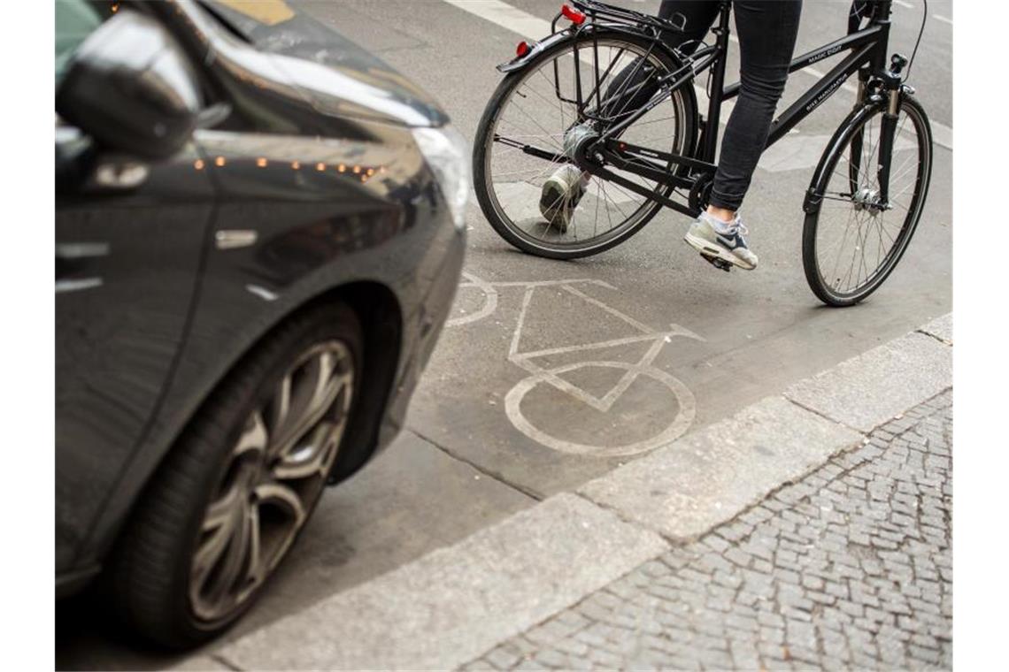 Eine Radfahrerin umfährt ein auf einem Radweg abgestelltes Auto. Foto: Alexander Heinl/dpa