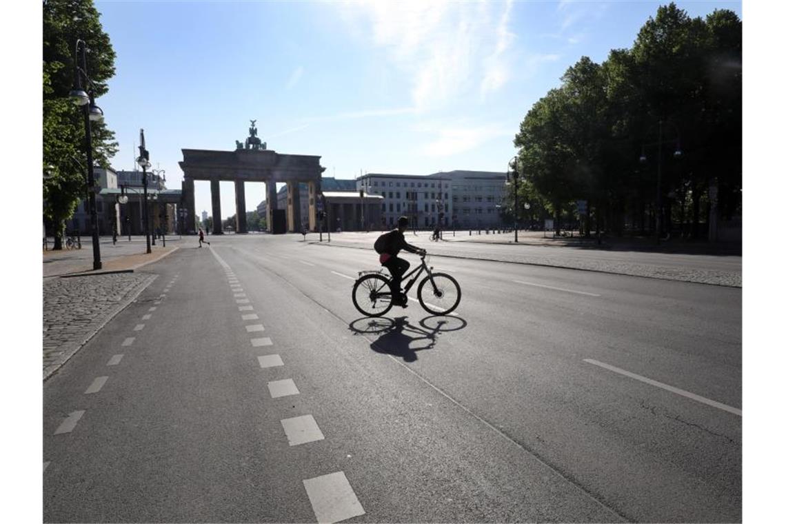 Eine Radfahrerin und ein Jogger sind auf der sonst verkehrsreichen Straße des 17. Juni vor dem Brandenburger Tor unterwegs. Foto: Wolfgang Kumm/dpa