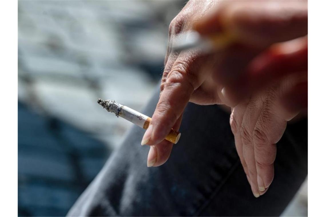 Bundestag stimmt für Tabaksteuer-Reform: Rauchen wird teurer Eine Raucherin hält eine brennende Zigarette in der Hand. Foto: Armin Weigel/dpa