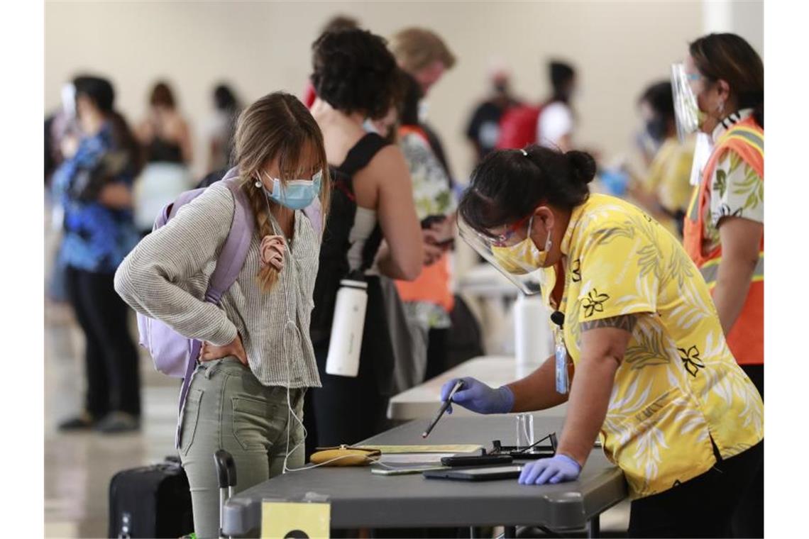 US-Tagesrekord: Mehr als 80.000 Corona-Neuinfektionen Eine Reisende auf Hawaii lässt sich vor einem Test beraten. Foto: Marco Garcia/AP/dpa