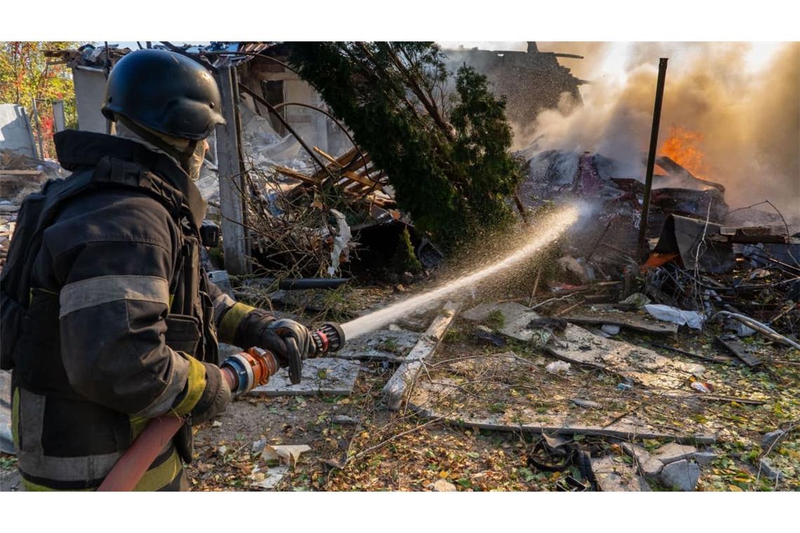 Eine Rettungskraft löscht einen Brand in Wohnhäusern, die bei einem russischen Angriff zerstört wurden.