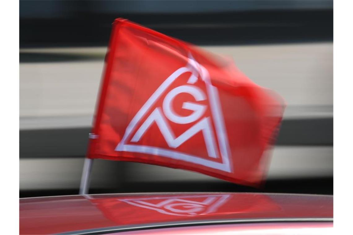 Eine rote IG-Metall-Flagge spiegelt sich in einem Fahrzeugdach. Foto: Patrick Seeger