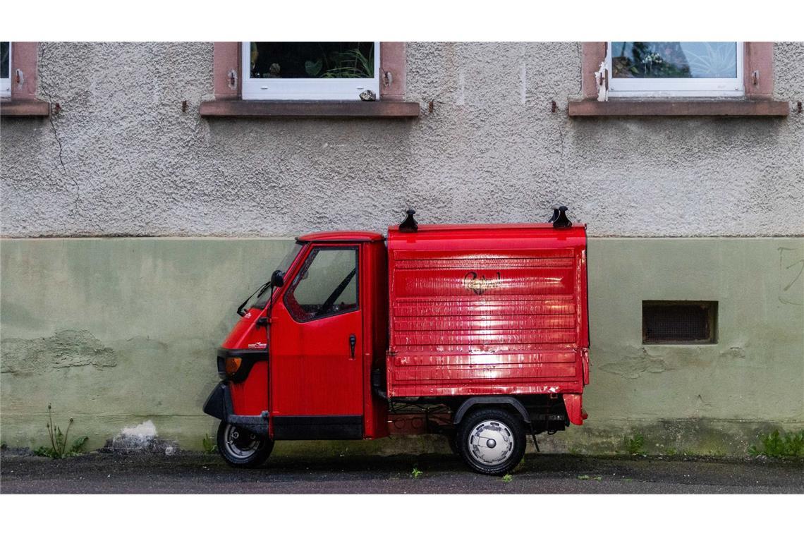 Italien trauert um die „Biene“ Eine rote Piaggio „Ape“ steht vor einem Haus.