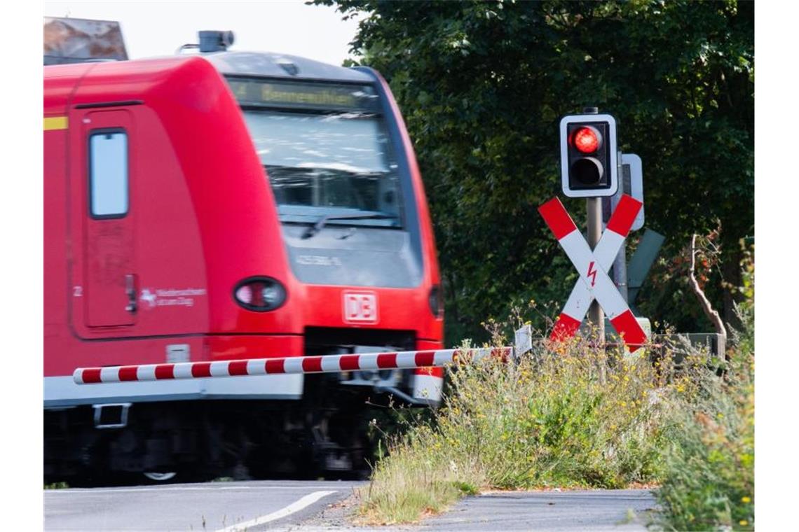 Eine S-Bahn der Deutschen Bahn (DB) fährt an einem Bahnübergang mit einer roten Ampel vorbei. Foto: Julian Stratenschulte/dpa/Archivbild