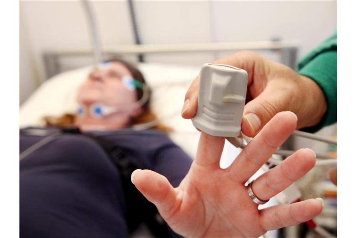 Eine Schlafpatientin wird von einem Krankenpfleger im Schlaflabor der Kliniken Essen-Mitte an Elektroden angeschlossen. Foto: Roland Weihrauch/dpa