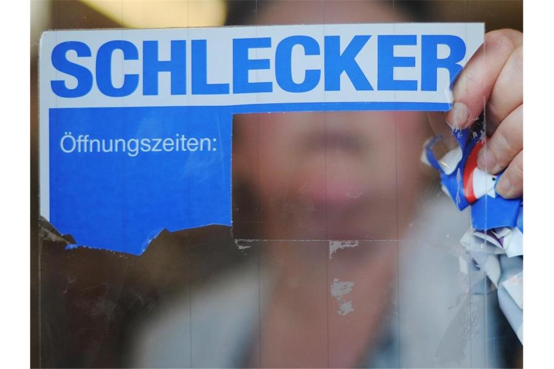 Vor zehn Jahren ging Schlecker insolvent Eine Schlecker-Mitarbeiterin reißt das Firmenlogo von der Eingangstür einer Filiale. Foto: picture alliance / Julian Stratenschulte/dpa