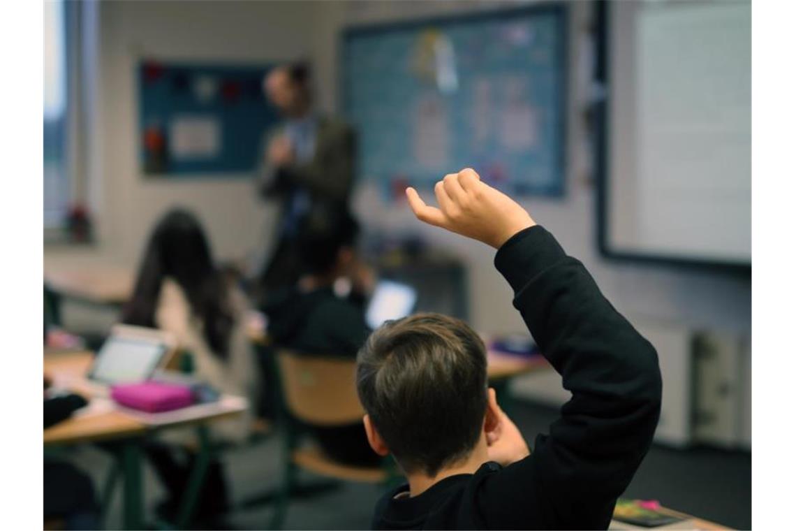 Eine Schüler hebt seine Hand hoch. Foto: picture alliance / Ina Fassbender/dpa/Archiv