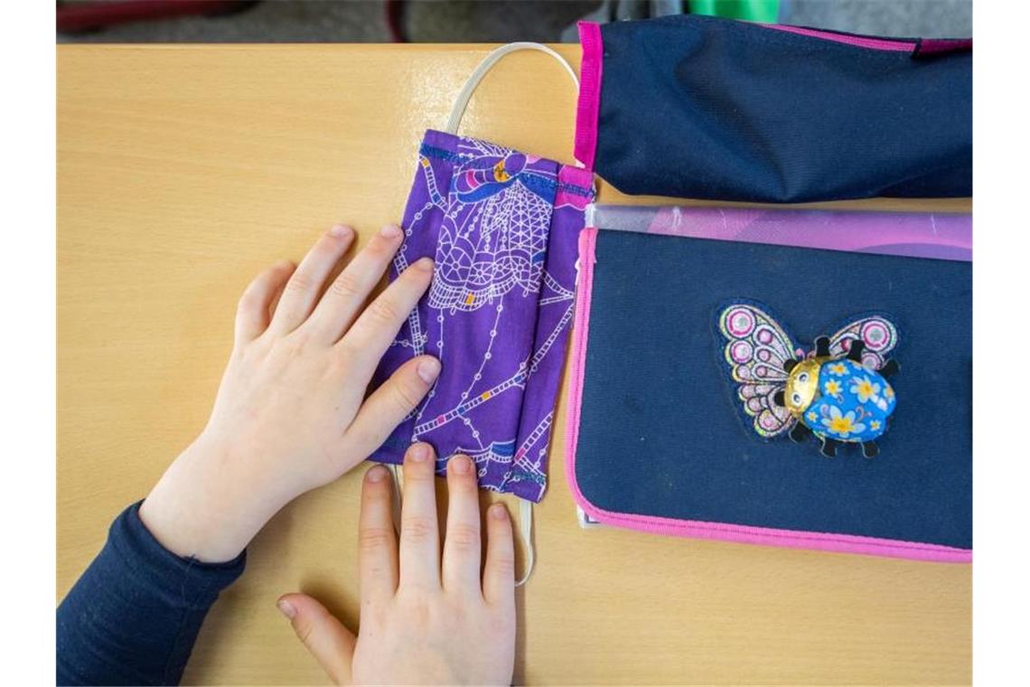 Berlin führt Maskenpflicht an Schulen ein Eine Schülerin einer Grundschulklasse legt ihren Mundschutz neben ihre Schulmappe. Foto: Robert Michael/dpa-Zentralbild/dpa