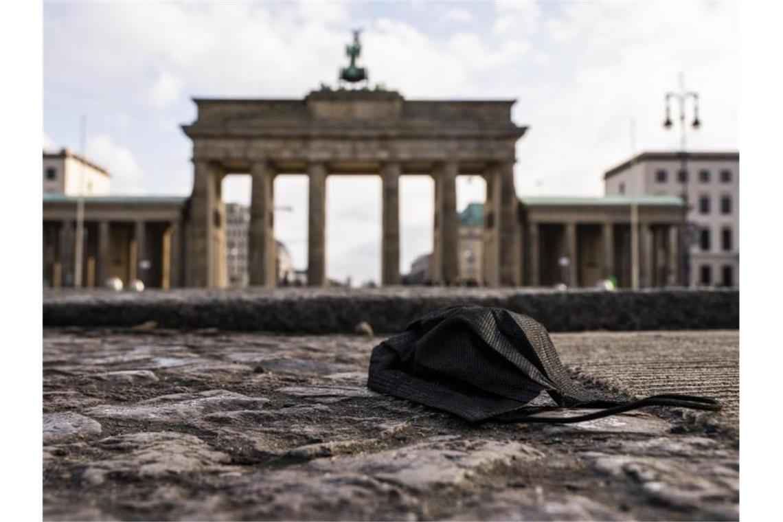 Umfrage: Mehrheit will baldige Lockerungen der Corona-Regeln Eine schwarze Corona-Makse liegt auf dem Boden vor dem Brandenburger Tor. Foto: Christophe Gateau/dpa