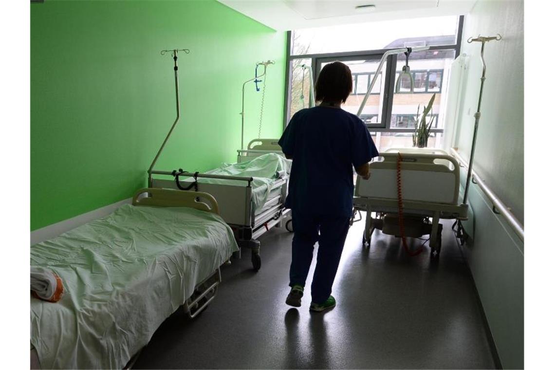 Eine Schwester steht in einem Krankenhaus und holt ein Bett. Foto: Patrick Seeger/dpa/Archivbild