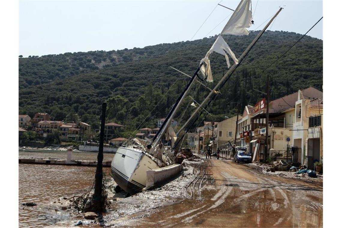 Drei Tote nach Stürmen in Griechenland Eine Segelyacht liegt nach einem Sturm neben einer Straße in Kefalonia. Der Wirbelsturm „Ianos“ im Westen und ein weiteres Sturmtief über der Nordägäis hatten am Freitag und Samstag in weiten Teilen Griechenlands schwere Schäden verursacht. Foto: Nikiforos Stamenis/AP/dpa