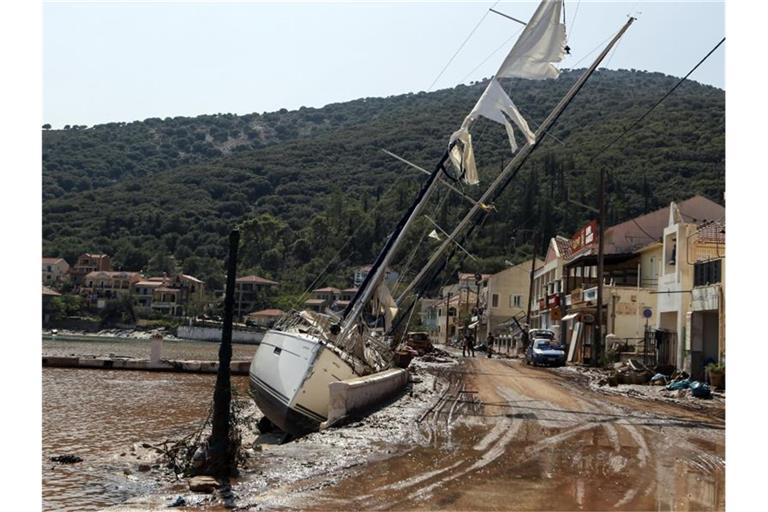 Eine Segelyacht liegt nach einem Sturm neben einer Straße in Kefalonia. Der Wirbelsturm „Ianos“ im Westen und ein weiteres Sturmtief über der Nordägäis hatten am Freitag und Samstag in weiten Teilen Griechenlands schwere Schäden verursacht. Foto: Nikiforos Stamenis/AP/dpa