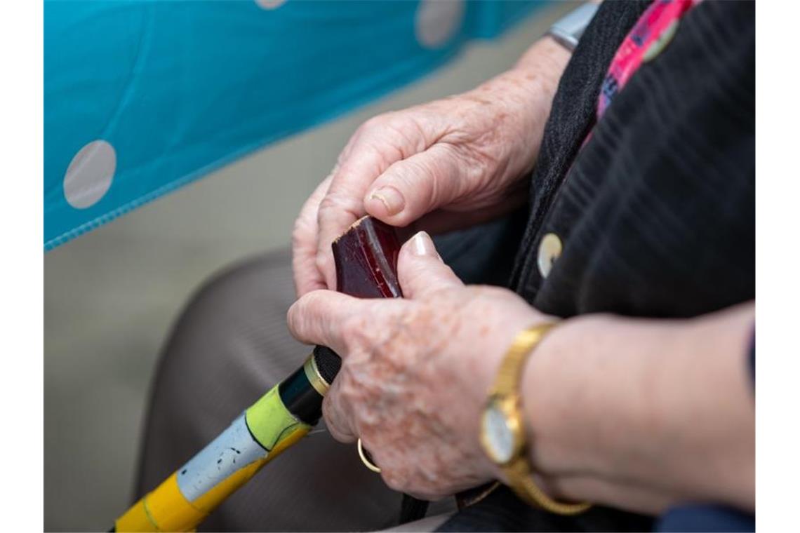 Eine Seniorin sitzt mit ihrem Gehstock im Garten eines Pflegeheims. Foto: Daniel Karmann/dpa