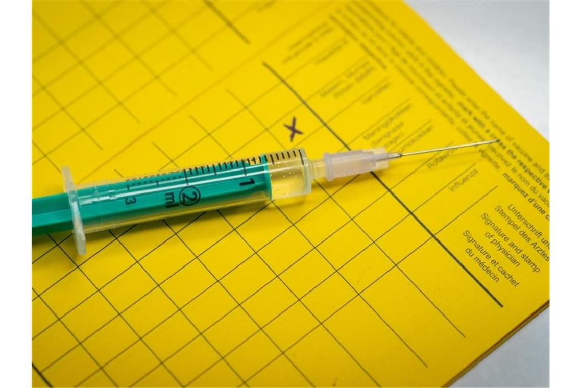 Arbeitgeber darf bei Quarantäne Impfstatus abfragen Eine Spritze liegt auf einem Impfpass. Foto: Friso Gentsch/dpa/Illustration