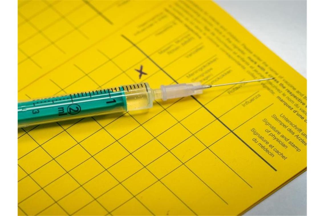 Südwest-Unternehmen verstärken Impfangebote Eine Spritze liegt auf einem Impfpass. Foto: Friso Gentsch/dpa/Illustration