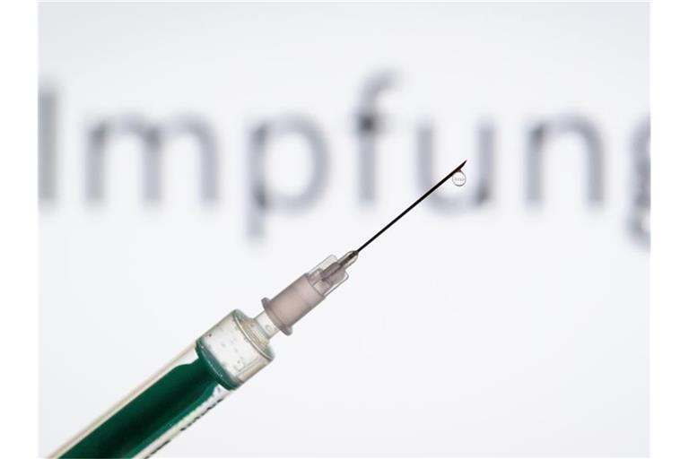 Eine Spritze wird vor den Schriftzug „Impfung“ gehalten. Foto: Friso Gentsch/dpa/Illustration