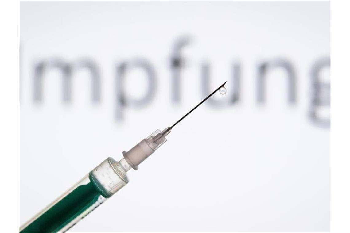 Eine Spritze wird vor den Schriftzug „Impfung“ gehalten. Foto: Friso Gentsch/dpa/Archivbild