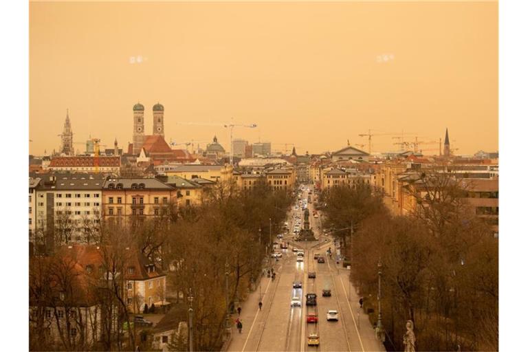 Eine Stadt in gelb und orange. Staub aus der afrikanischen Wüste färbt den Himmel in München. Foto: Sven Hoppe/dpa