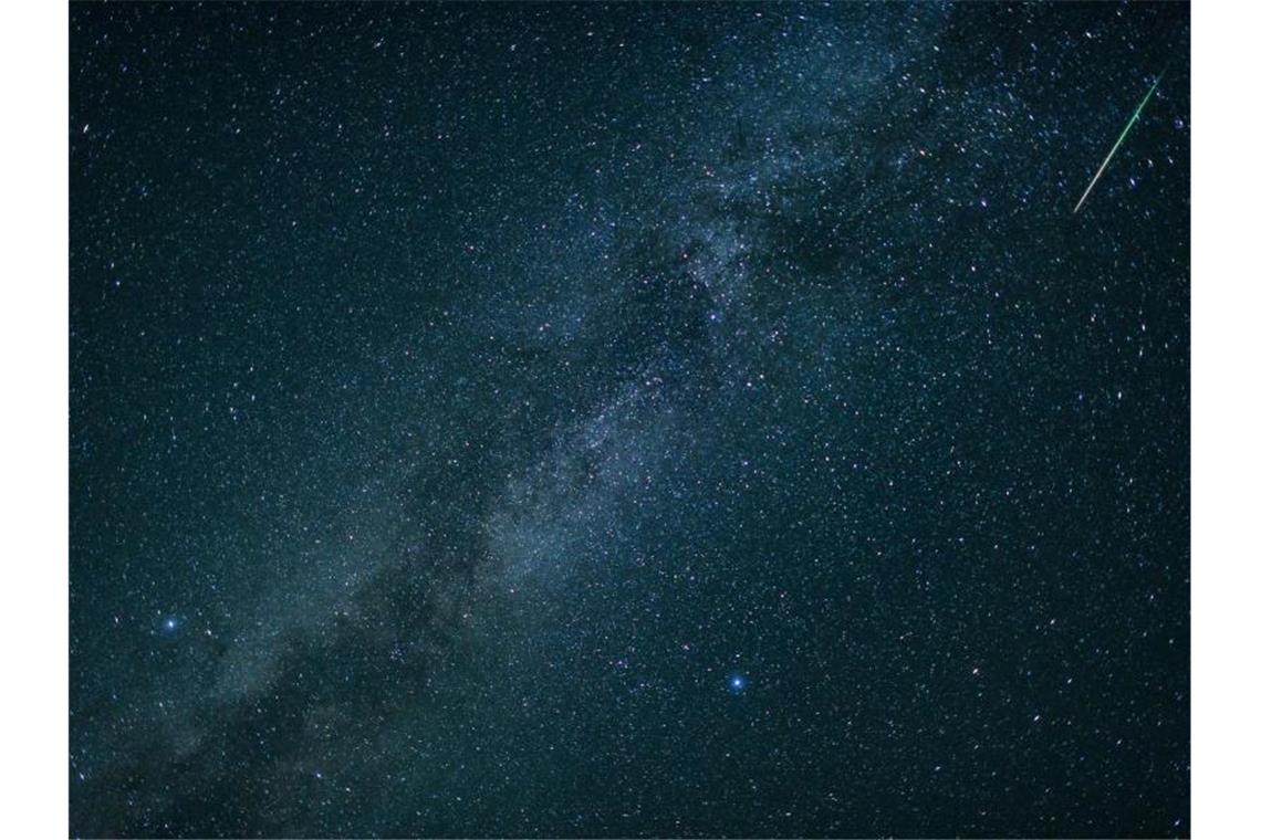 Eine Sternschnuppe leuchtet neben der Milchstraße am Himmel über dem Walchensee. Foto: Matthias Balk