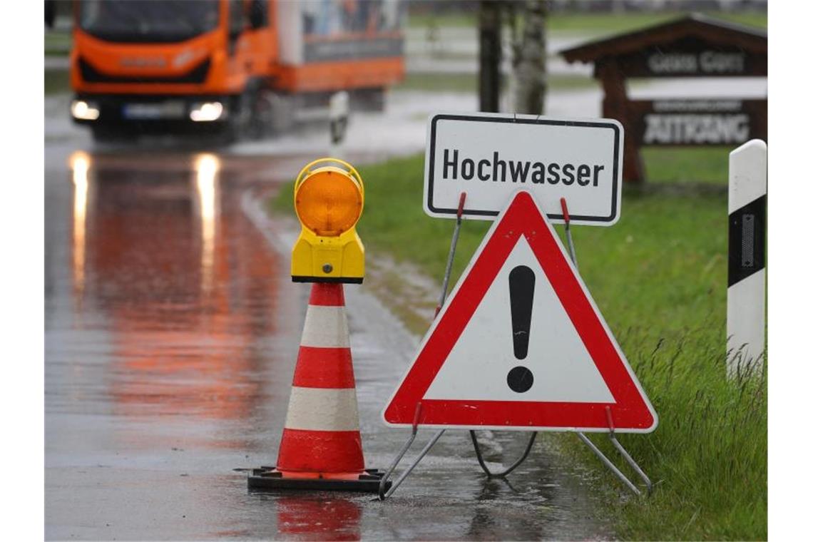 Eine Straße in Bayern ist vom Wasser eines über die Ufer getretenen kleinen Baches überschwemmt. Foto: Karl-Josef Hildenbrand