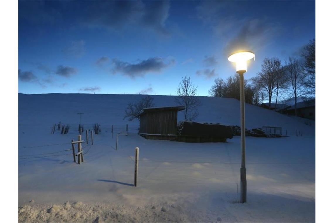 Eine Straßenlampe steht am frühen Morgen in winterlicher Landschaft. Foto: Karl-Josef Hildenbrand/dpa/Symbolbild