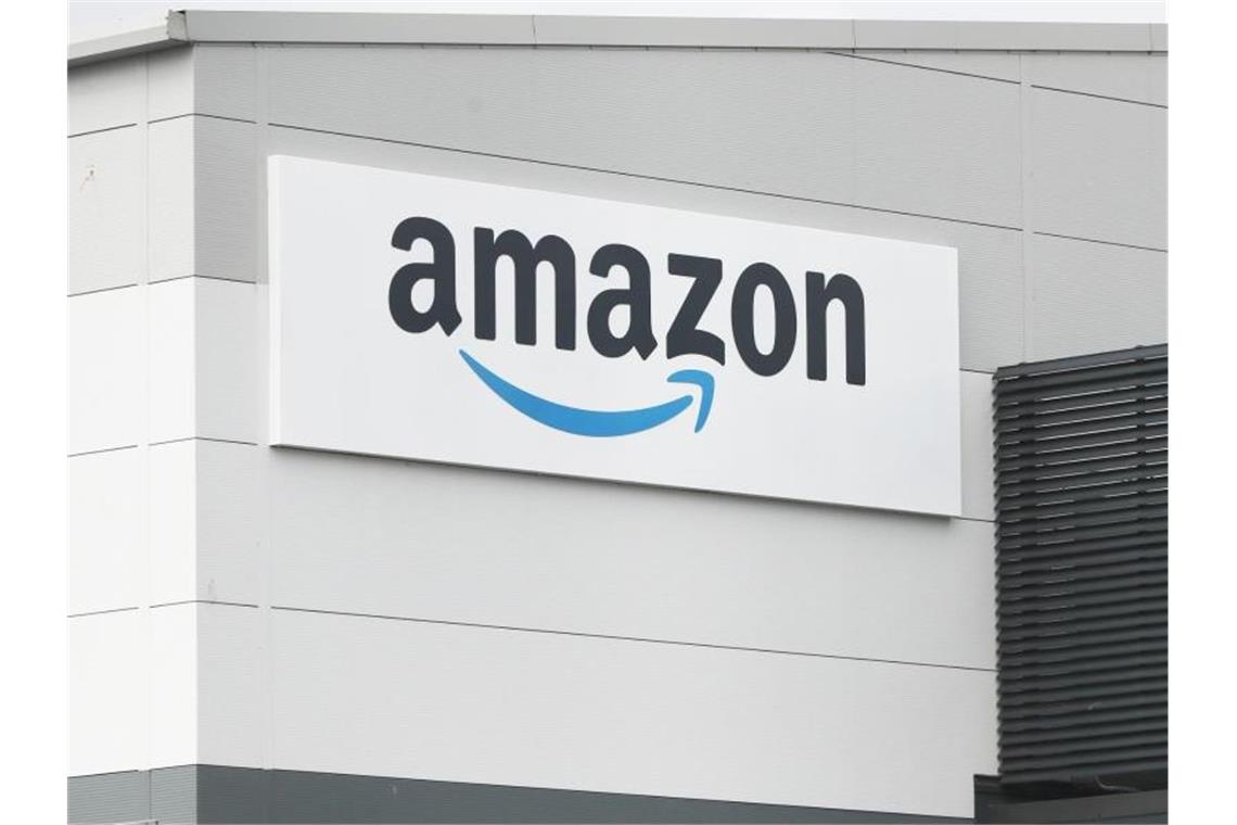 Eine Tafel mit dem Logo des Onlineversandhändlers Amazon ist an der Fassade eines Amazon-Warenlagers angebracht. Foto: Niall Carson/PA Wire/dpa
